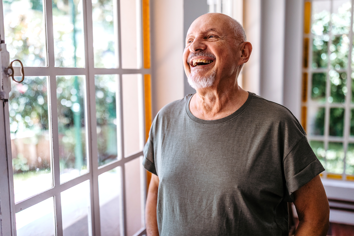 Man standing near a window smiling at Milestone Retirement Communities 