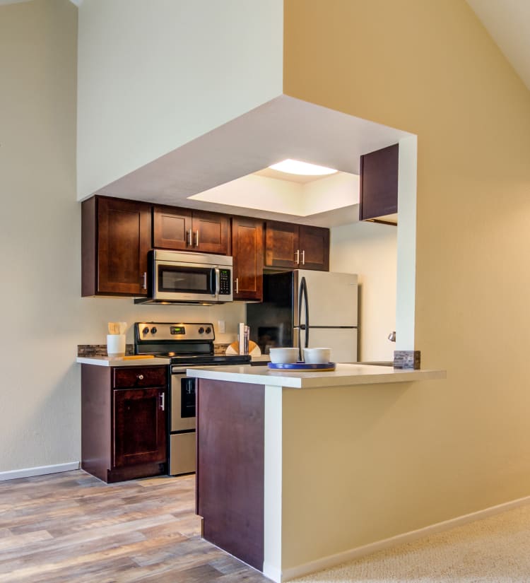 Modern kitchen with rich, cherry wood cabinetry in a model home at Sofi Lake Oswego in Lake Oswego, Oregon