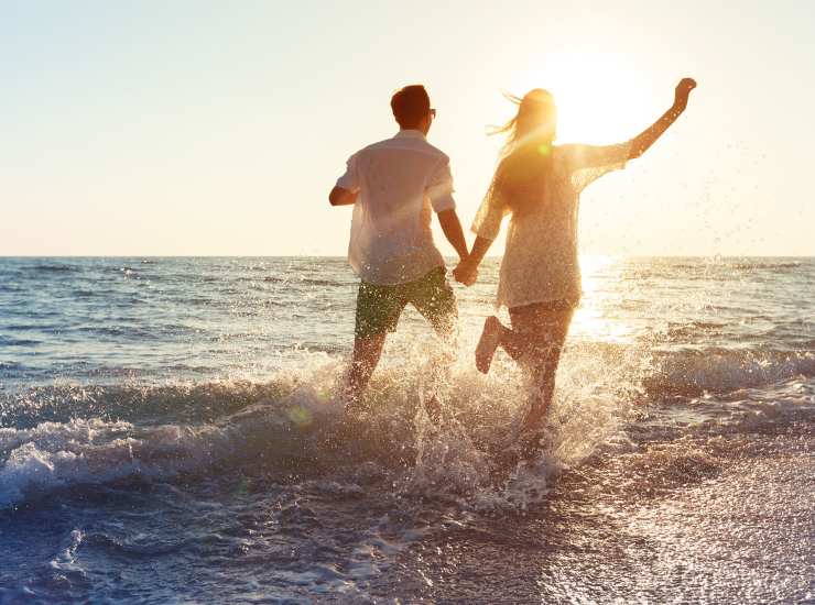 A couple running through water on a beach near Cloisters at Carolina Forest in Myrtle Beach, South Carolina