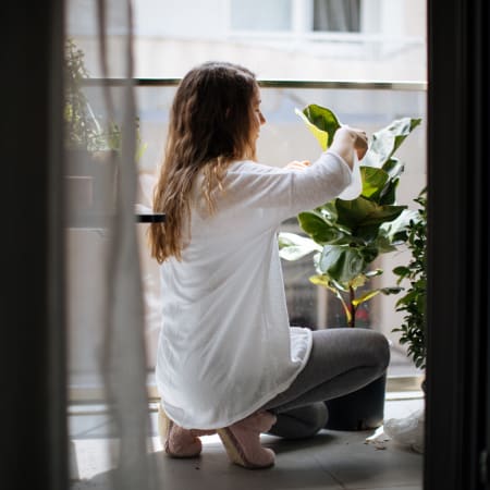 Resident watering a plant on her private balcony at Auberge of Tyler in Tyler, Texas
