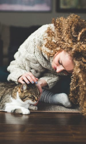 Resident giving her cat a scratch in the living room of their home at Willow Glen in Fort Worth, Texas