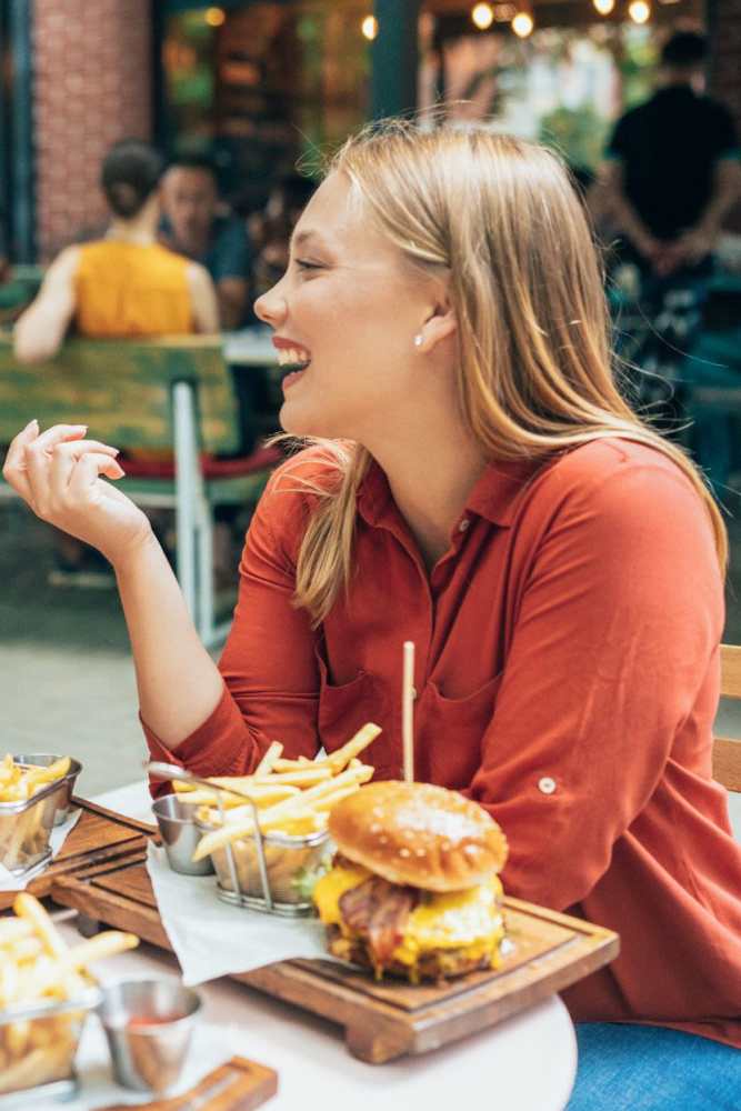 A woman eating a burger near Foxwood Apartments in Doraville, Georgia