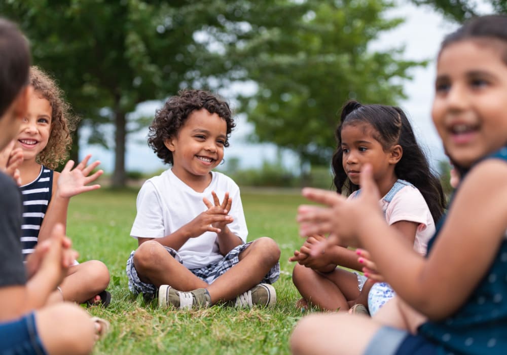 A group of kids sitting in a circle at a park near Villa Bella in Euless, Texas