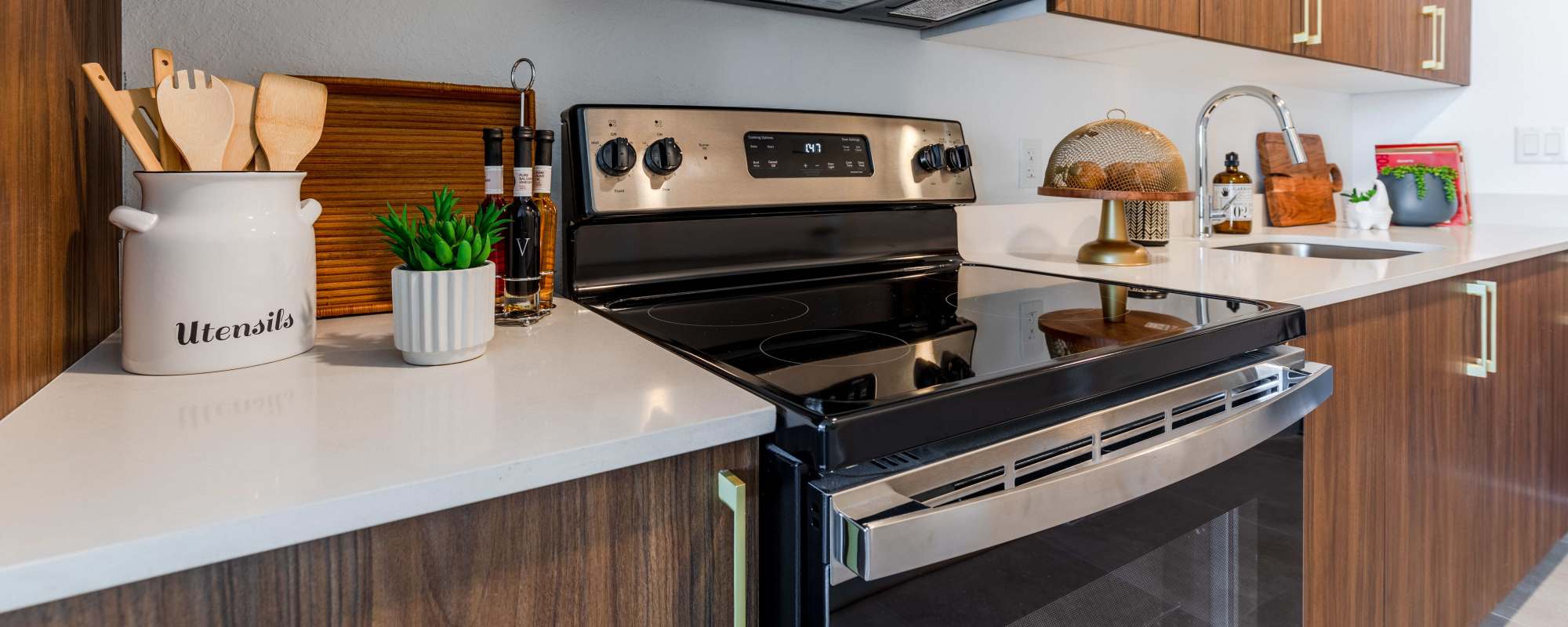 Kitchen with range, oven, marble countertop and wooden cabinetry at Alture Westland in Hialeah, Florida
