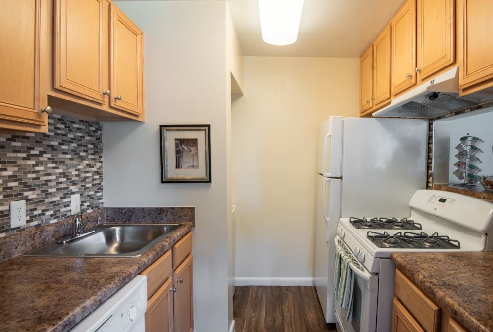 Kitchen with white appliances and maple cabinets at Harbor Place Apartment Homes in Fort Washington, Maryland