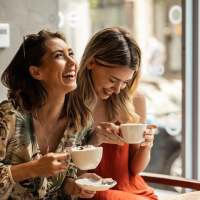 Best friends sharing a laugh while having coffee near Adams Crossing in Waldorf, Maryland