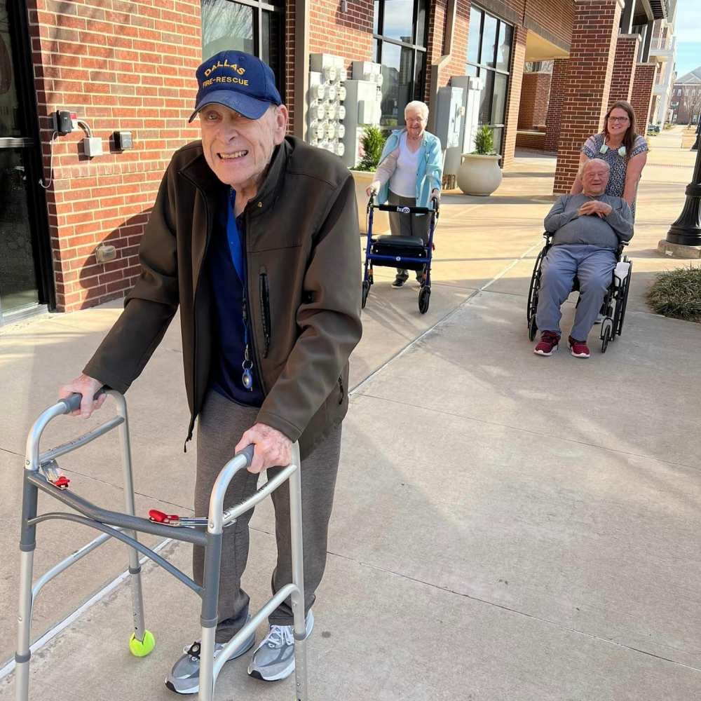 Residents enjoying outdoor mobility time with walkers and wheelchairs near Watermere Frisco memory care center.