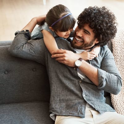 Father and daughter hugging in living room at Coral Sea Park in Lemoore, California