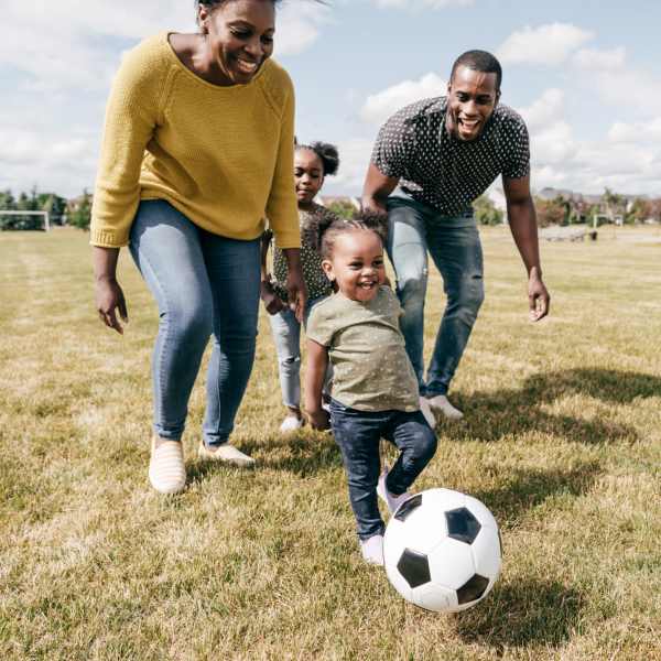 Family playing soccer on grassy field near Valley Brook Townhomes in Rochester, New York