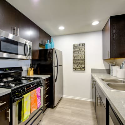 Modern kitchen with granite countertops and stainless-steel appliances in a model home at Sofi at 3rd in Long Beach, California