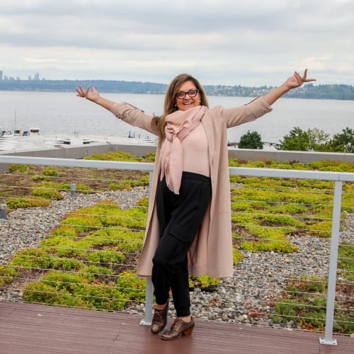 An employee with her hands up to emphasize the beautiful scenery at Pillar Properties in Seattle, Washington