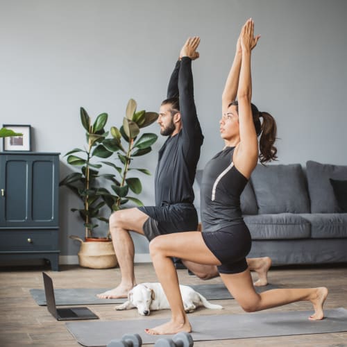 Couple practicing yoga in the living room of their new home at Solaire 8200 Dixon in Silver Spring, Maryland