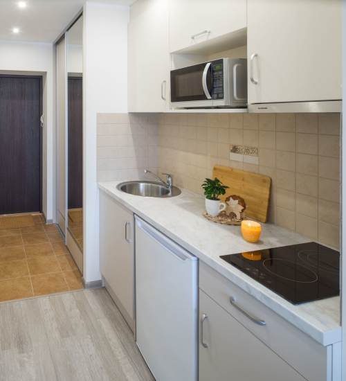 Modern kitchen with stainless steel appliances, granite countertops, and wood-style flooring at Jordache Park Apartments in Spencerport, New York