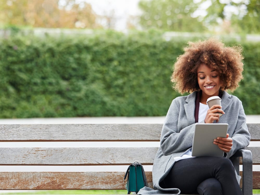 Resident sitting on her computer at a nice park area in town near Knoll at Fair Oaks in Fairfax, Virginia