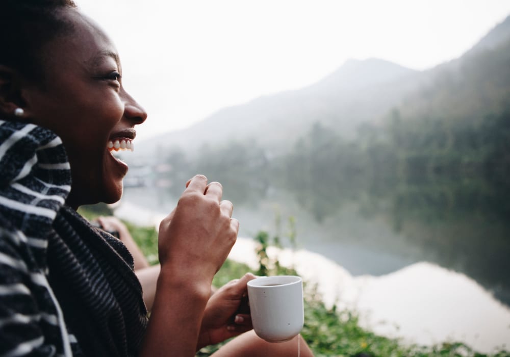Woman with a cup of coffee enjoying the view of the misty mountains and river near Mountain Glen Apartments in Glen Lyn, Virginia