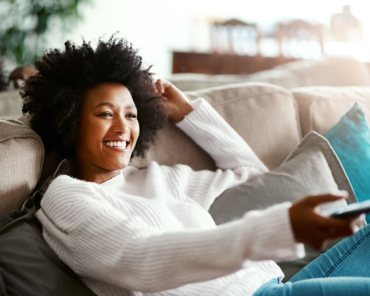 Resident watching TV on her couch at Carrington Apartments in Fremont, California