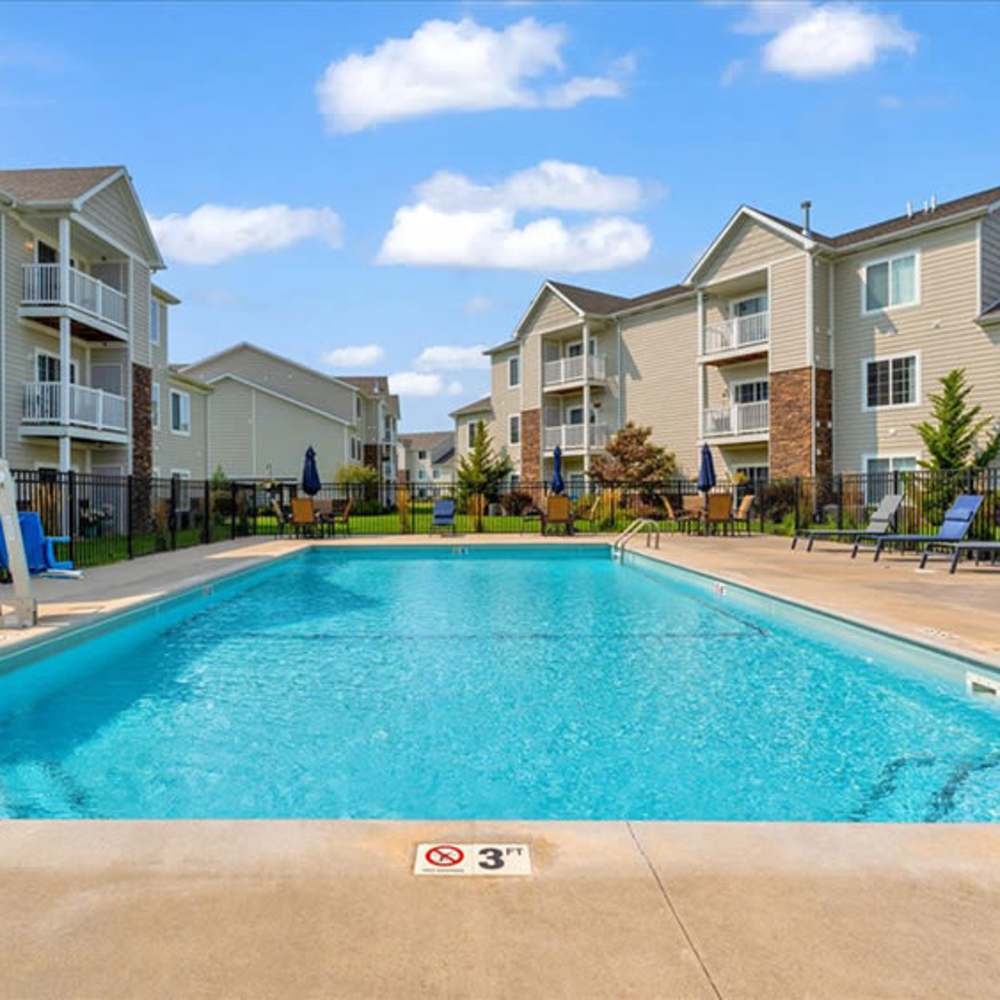 A swimming pool with exterior building view at The Haven at Grand Landing Apartments in Grand Haven, Michigan