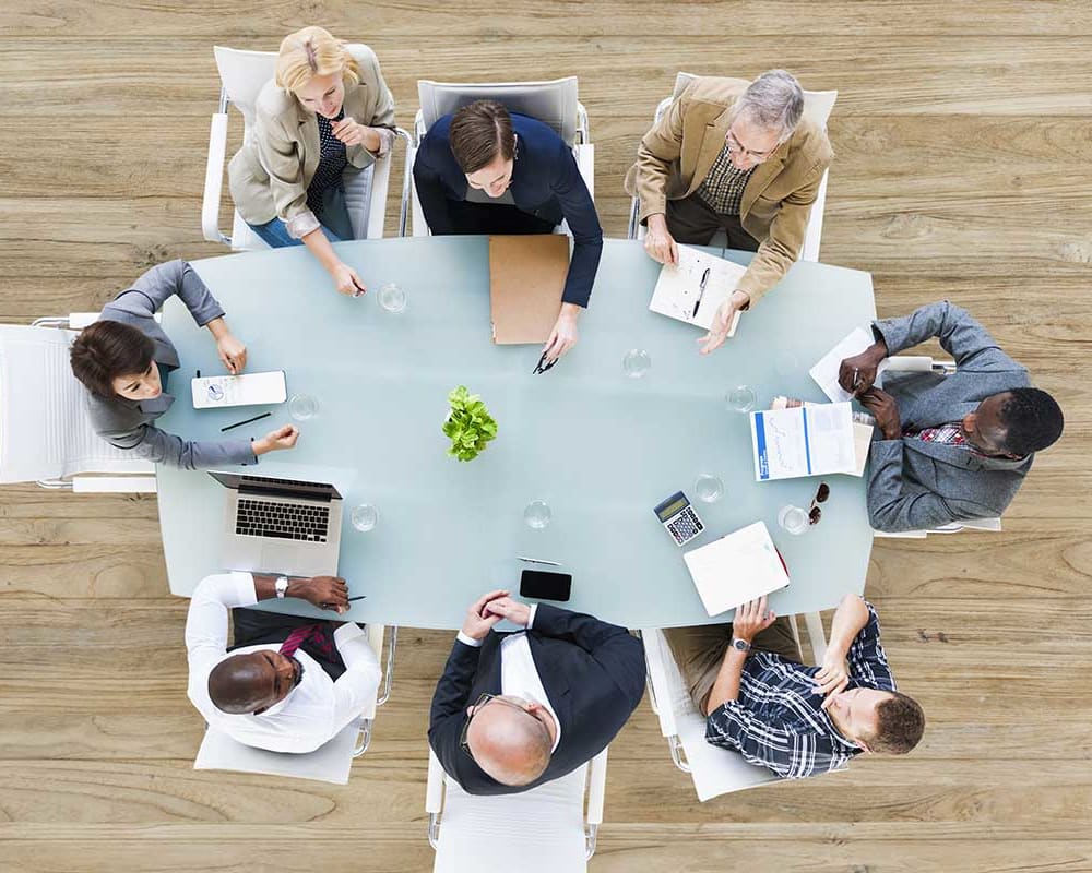 Overhead view of employees at a meeting around a table at American Capital Group in Bellevue, Washington