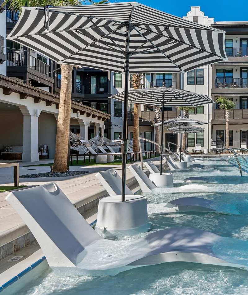 Swimming pool with in-pool lounge chairs at Palmilla | Luxury Apartments & Townhomes in Pensacola, Florida