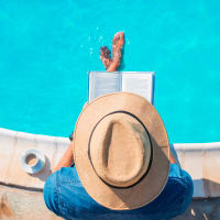 A man reading with his feet in the swimming pool at Cypress McKinney Falls in Austin, Texas