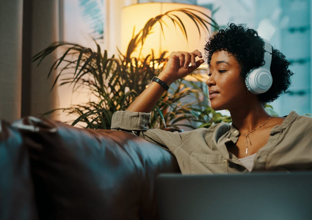 Woman listening to music on her couch at Woodstream Townhomes in Rocklin, California