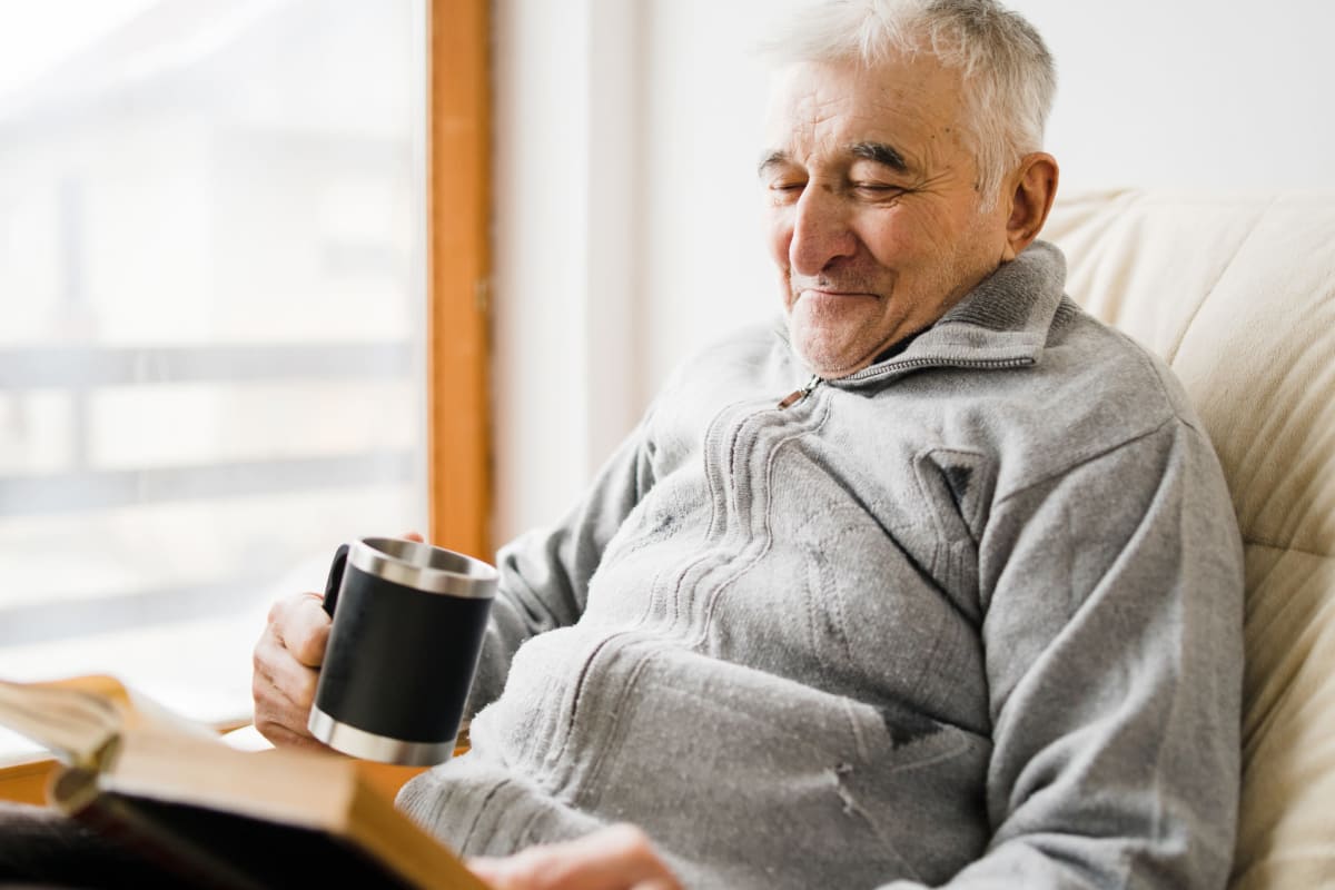 Resident reading with coffee at Madison House in Norfolk, Nebraska