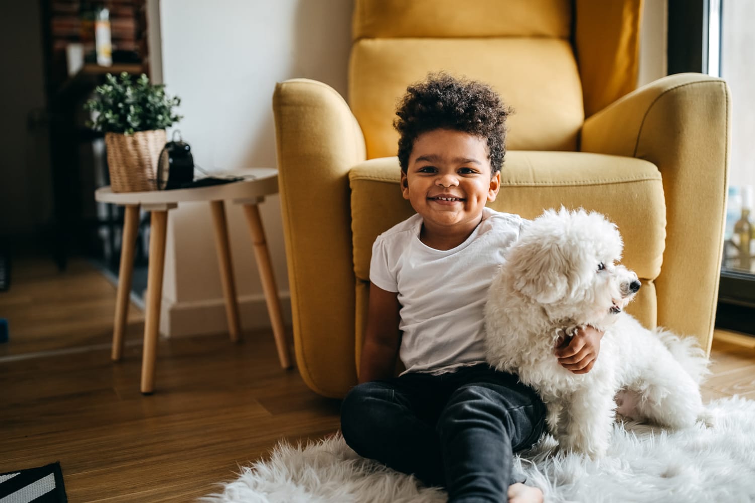 Cute kid and puppy sitting on the ground at home at Reserve at South Creek in Englewood, Colorado