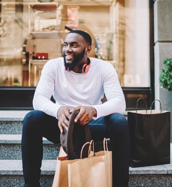 A man with shopping bags sitting on steps in front of a shop near EOS in Orlando, Florida