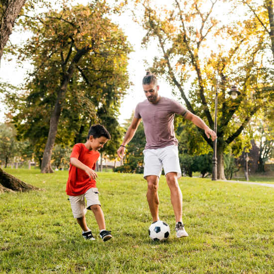 Father and son playing football in park at Haggerty Lane in Bozeman, Montana