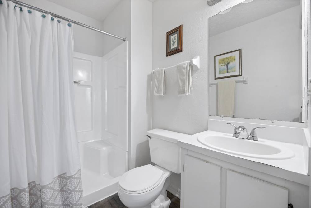 Modern bathroom with mirror, sink, commode and shower at Carlton Arms Of South Lakeland in Lakeland, Florida