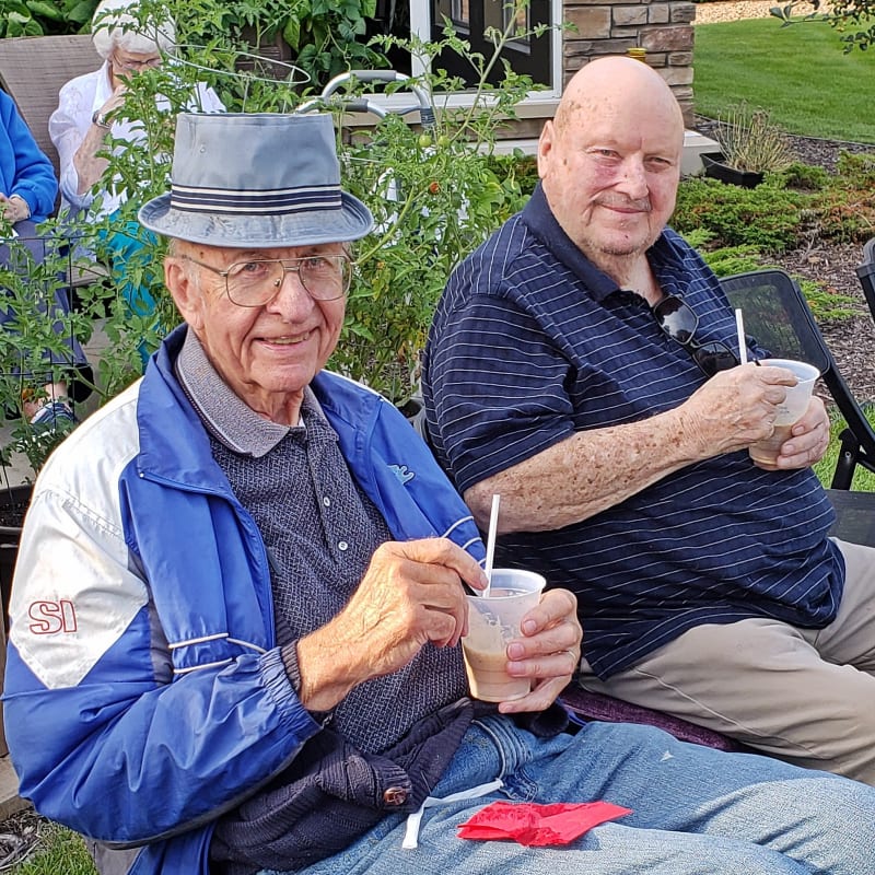 Residents enjoying beverages outside while sitting on a bench at Meadows on Fairview in Wyoming, Minnesota