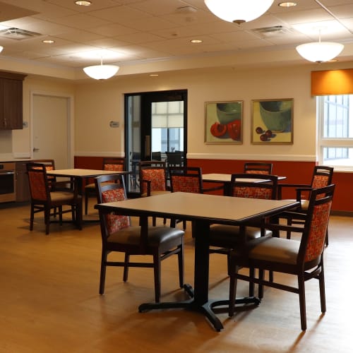 Causal resident dining hall with tables and kitchen amenities at First & Main of Bloomfield Township in Bloomfield Township, Michigan