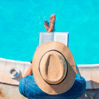 A man sitting on the edge of the swimming pool reading a book at Residences at Congressional Village in Rockville, Maryland