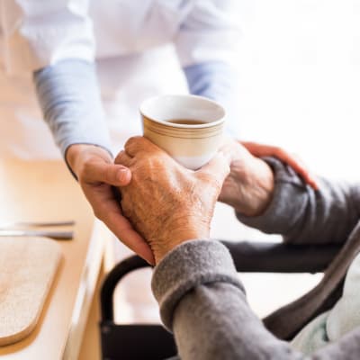 Staff handing a resident a cup of coffee at Westminster Memory Care in Lexington, South Carolina