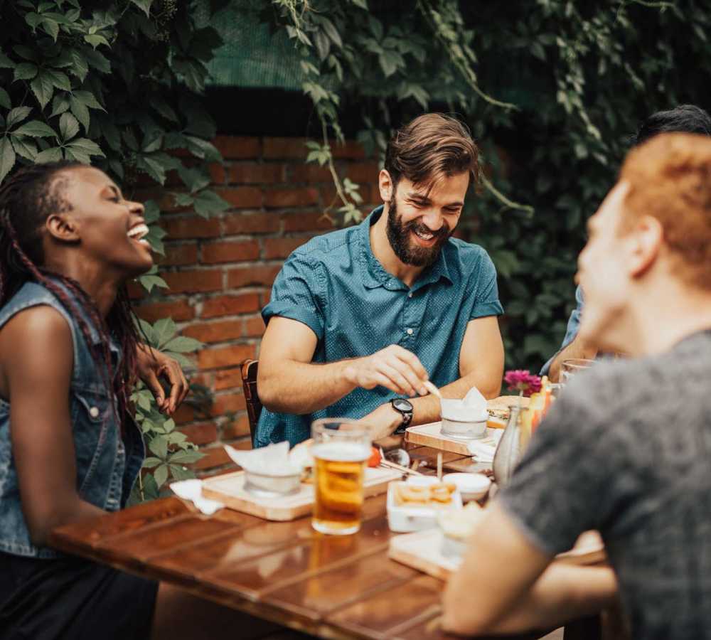 Group of people laughing around a table near Avia Lofts at Maple Road in Amherst, New York 