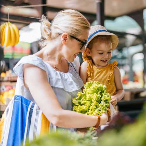 Woman holding green lettuce with child nearby near Avia Lofts at Maple Road in Amherst, New York