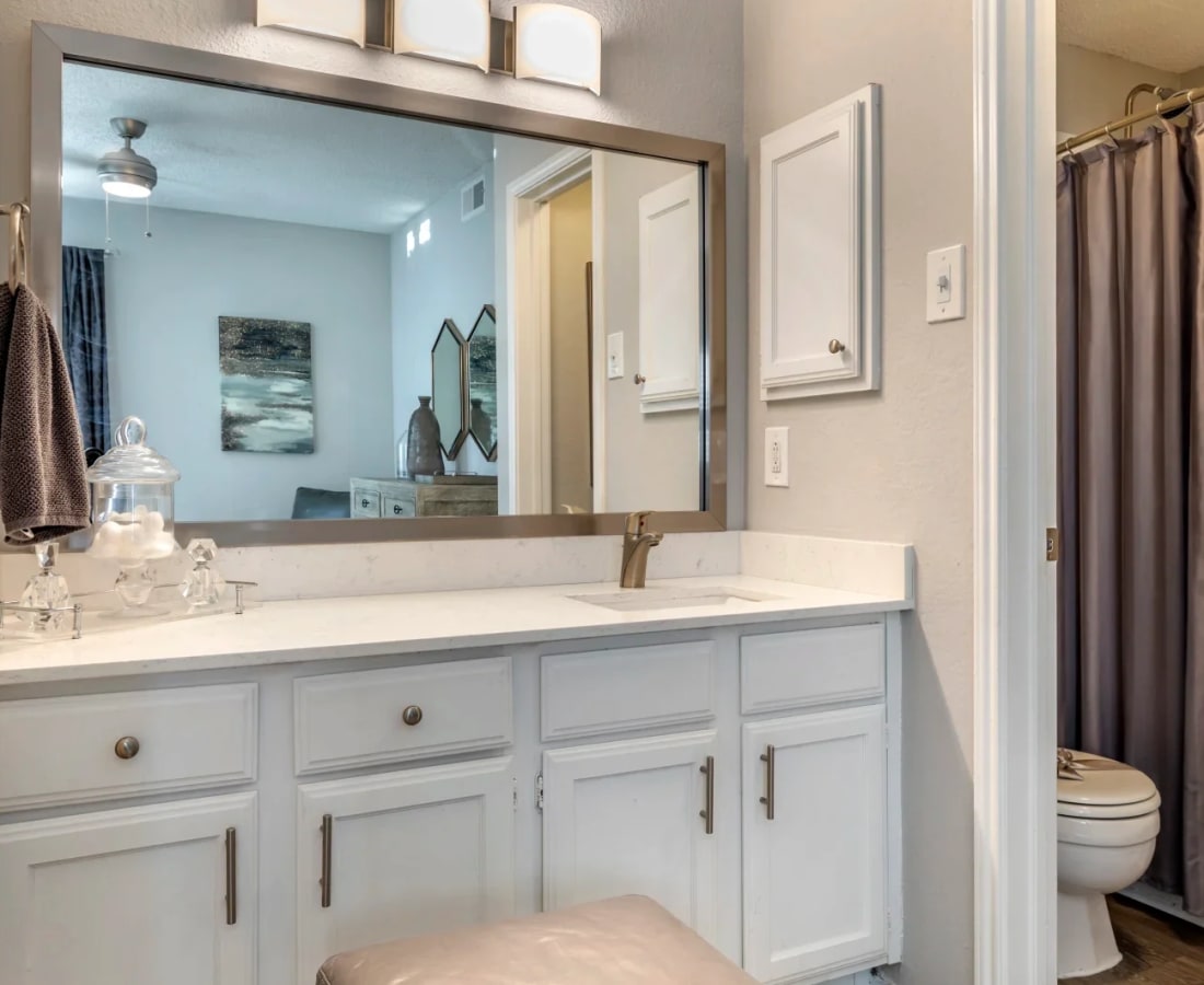 Model bathroom with oversized vanity with custom white cabinetry at The Brandt in Irving, Texas