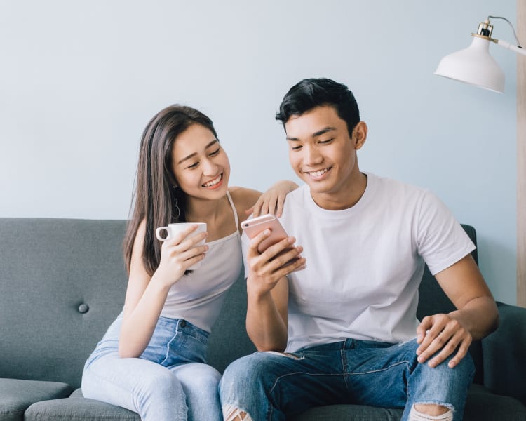 Resident couple browsing the web on a mobile device in their apartment home at Sofi Highlands in San Diego, California