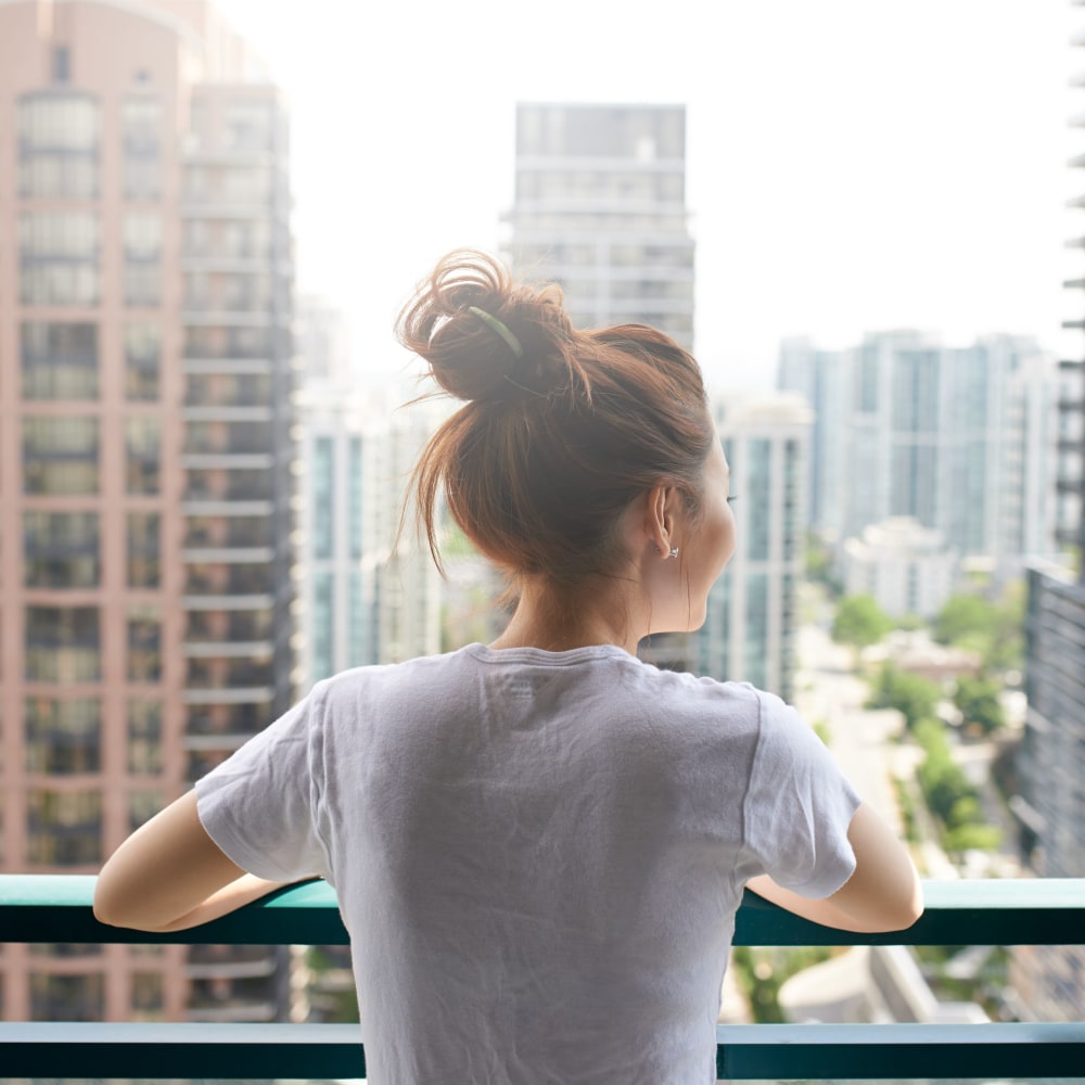 Resident overlooking the city on a balcony near 55 Brighton at Packard Crossing in Boston, Massachusetts