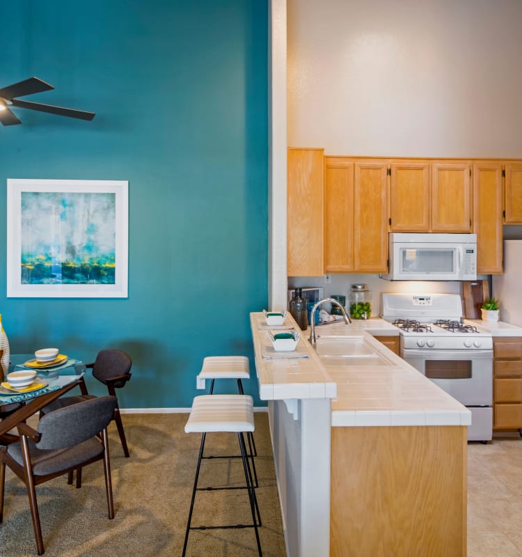 Split view of the dining and kitchen areas from the living space of a model home at Sofi Canyon Hills in San Diego, California
