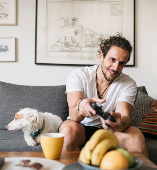 A resident relaxing on his couch with his dog playing a game at Heritage at Riverstone in Canton, Georgia