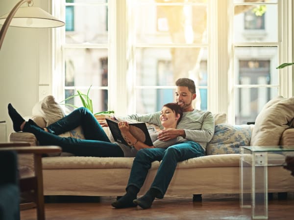 Resident couple laying on the couch reading a book at TerraLane at South Mountain in Phoenix, Arizona