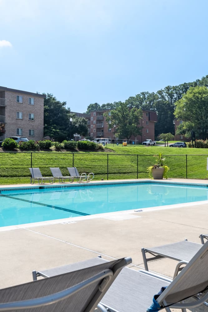 Swimming pool surrounded by lounge chairs at The Willows Apartment Homes in Glen Burnie, Maryland