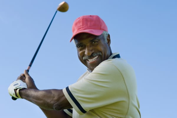Senior man swinging golf club