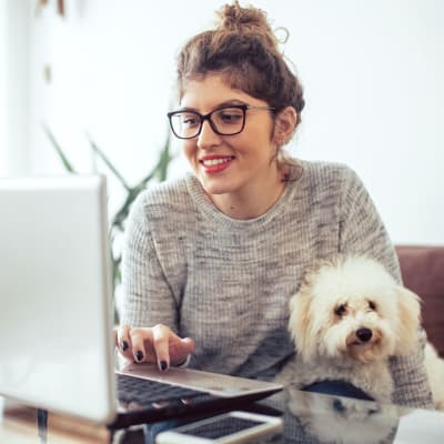 A resident working on a computer with her dog in her lap at Villa Bella in Euless, Texas