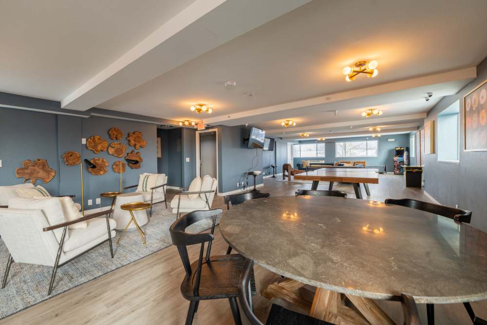 Resident lounge with flat screen TVs, table games, and arcade games, with kitchenette at Thea Apartments in Tacoma, Washington