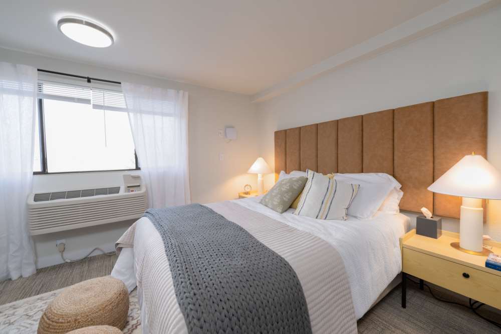 Furnished model apartment home with queen size bed with headboard at Thea Apartments in Tacoma, Washington.