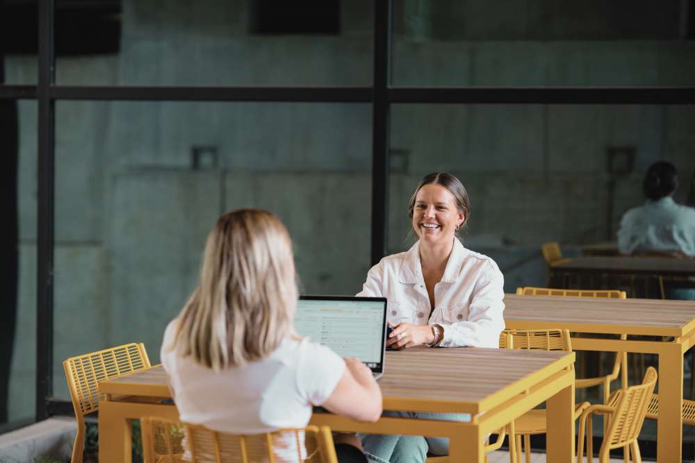 Two residents at a table with a laptop near St. Albans Lofts in Raleigh, North Carolina