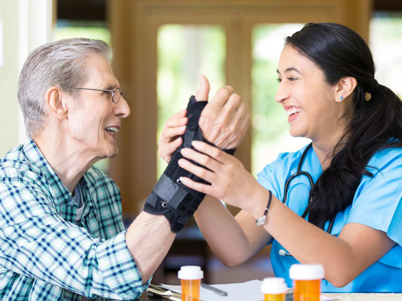 Resident having his wrist brace being adjusted by a caregiver at The Residences on Forest Lane in Montello, Wisconsin