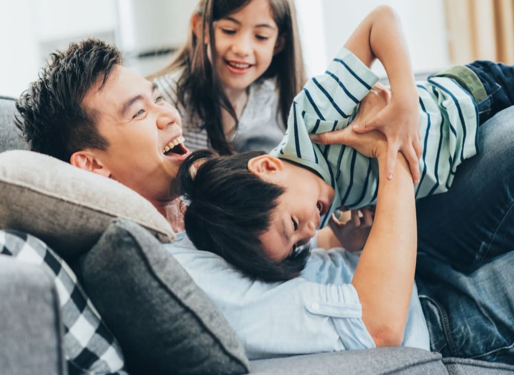 A resident playing on the couch with his kids at Vista Ridge in Vista, California